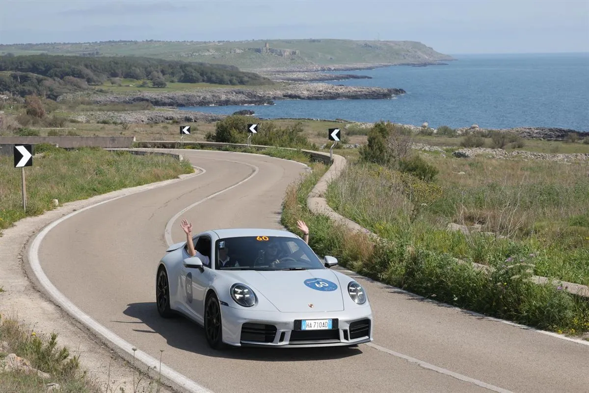 Car 60, a silver coupe, on a winding coastal road above the sea in southern Italy