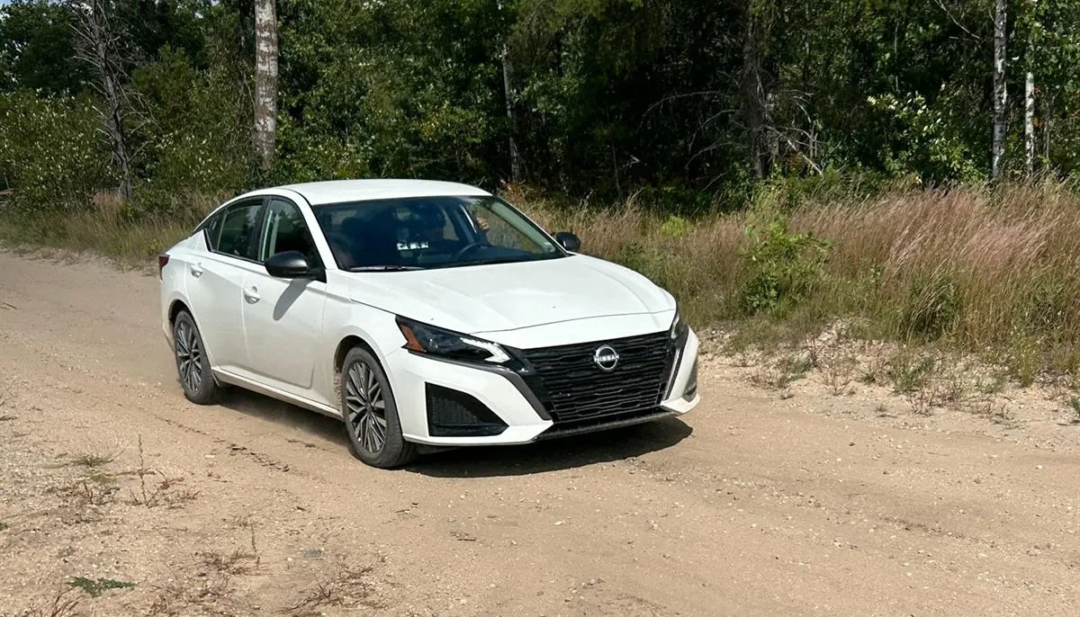 A white Nissan Altima on a sandy forest road during Press On Regardless in Michigan